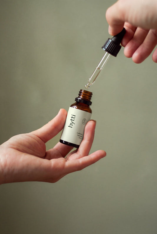 Hands holding a dropper over a 20 ml Hytti Caffeine Facial Gel bottle