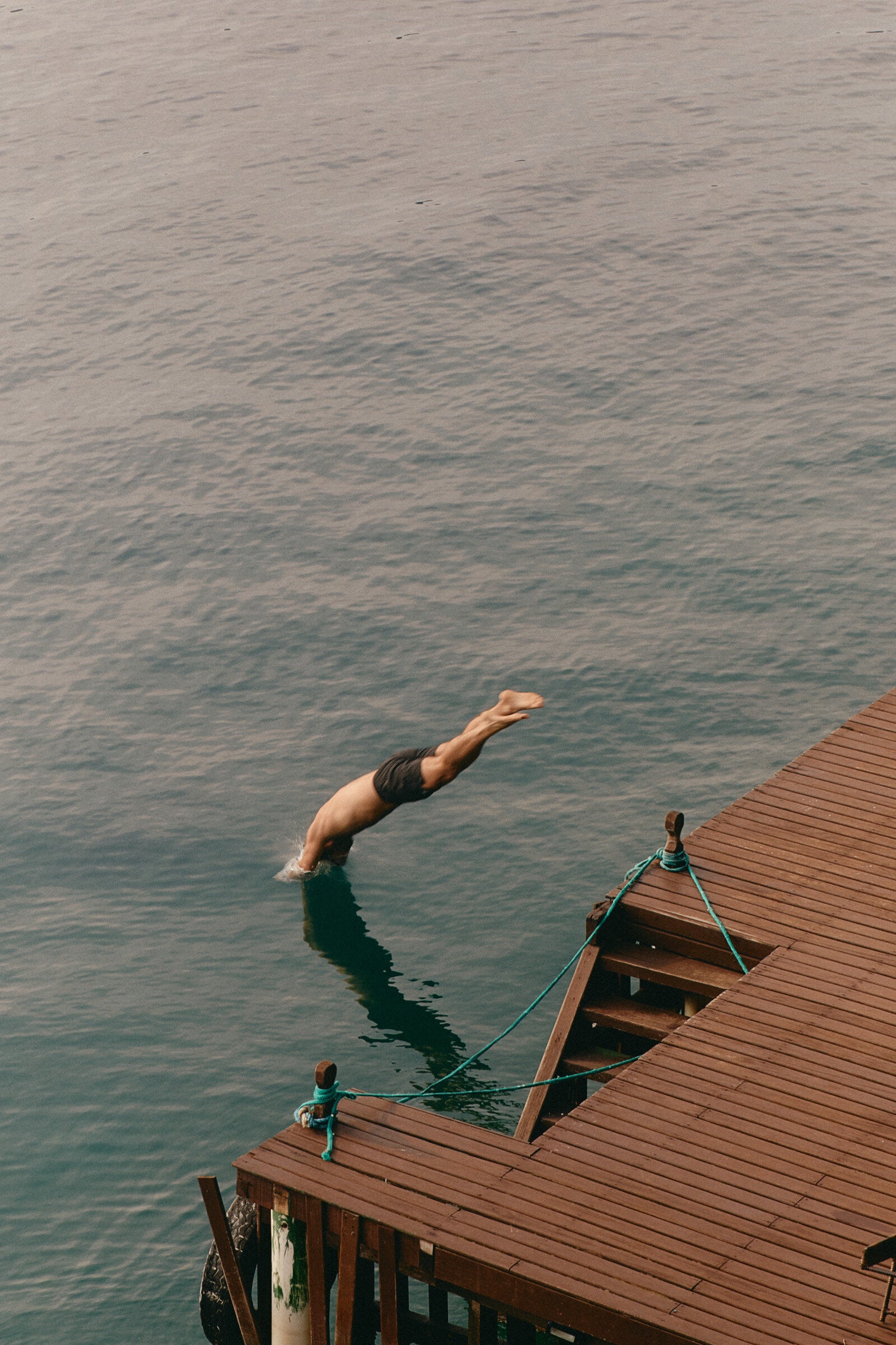 A man diving off a wooden jetty into a lake